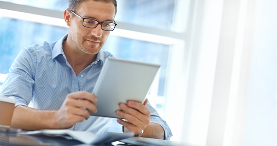 A middle-aged man reads about preventative care options on his tablet. He looks relaxed and thoughtful